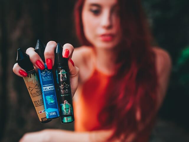 girls holds several vape juice bottles